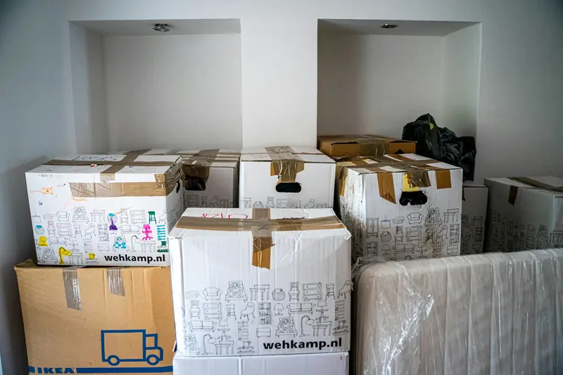 Des cartons fermés avec du ruban adhésif et un colis emballé, regroupés à l'intérieur d'un logement.